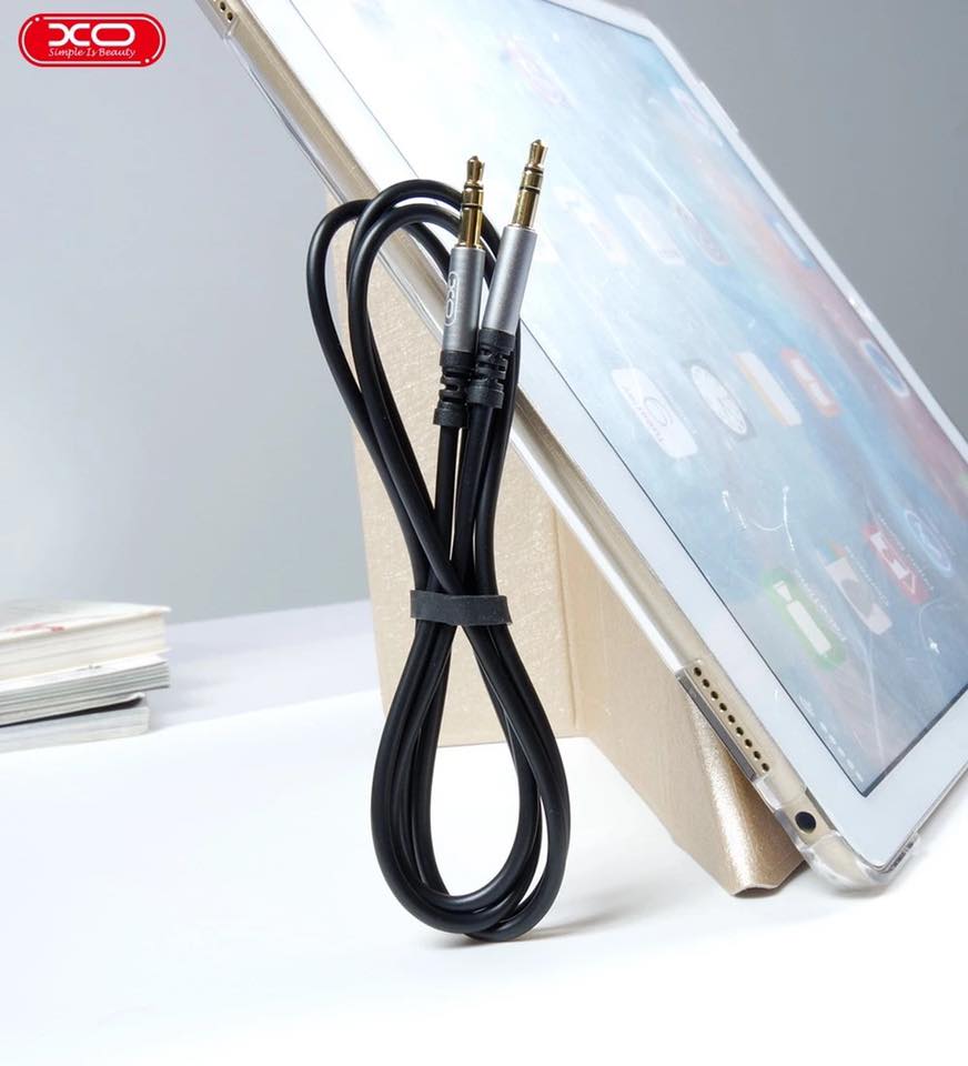 Cable AUX XO NB121 conectado a teléfono en auto, mostrando flexibilidad.